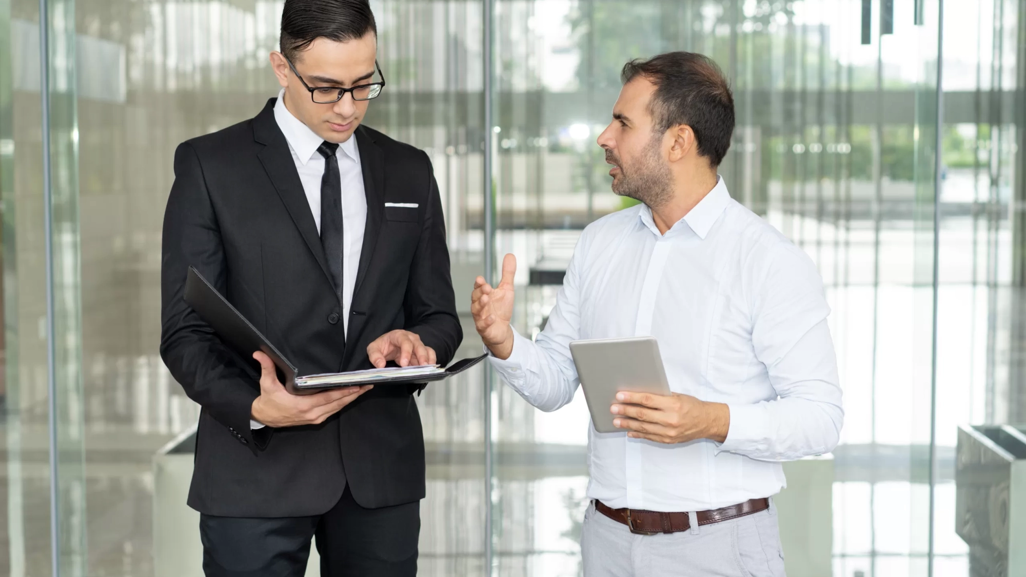 Emotional businessman with tablet computer proving his point to coworker. Financial manager reading document when listening to arguments of his colleague. Business conversation concept